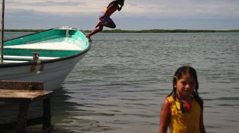 Children in Baja Mexico playing in water jumping off fishing boat Stock Footage