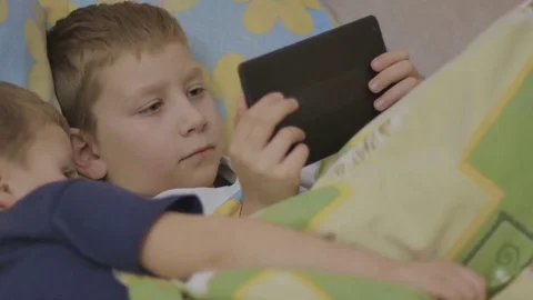 Children on bed with online device 스톡 동영상 75876614
