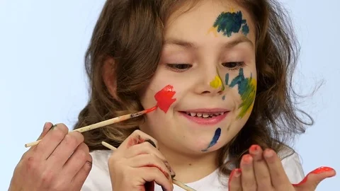Children begin to paint on their faces with tassels. White background. Slow Stock Footage 76129225