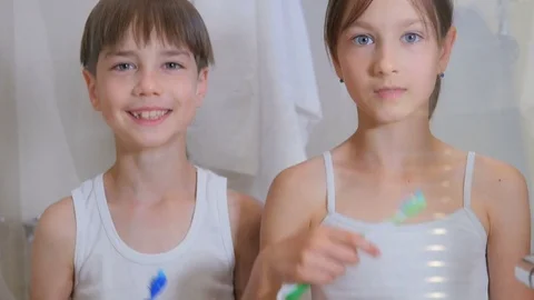 Children brush their teeth. A boy and a girl brush their teeth in the bathroom.  Stock Footage 77553626