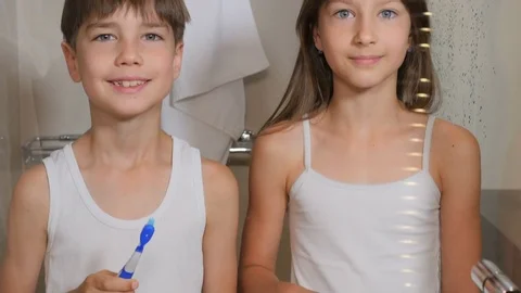 Children brush their teeth. A boy and a girl brush their teeth in the bathroom.  Stock Footage 77558271