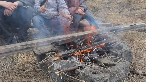 Children burn a bonfire on the background of an old destroyed wooden house Stockbeeldmateriaal 74948561