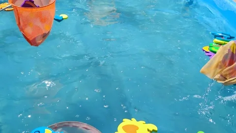 Children catch toys with nets in a pool with blue water Stock Footage 196487863
