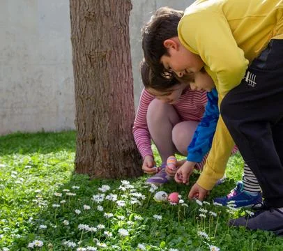 Children celebrating easter finding eggs in grass Stock-Fotos