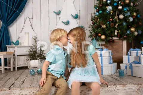 Children at the Christmas tree. look at each other. touch their heads Stock Photos