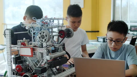 Children in a class at a robotics lesson assemble modules for the moving robot Stock Footage 243313099