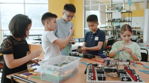 Children in a class at a robotics lesson sitting at the table and assembling Stock Footage 242170107
