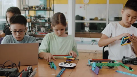 Children in a class at a robotics lesson sitting at the table and assembling Stock Footage 242170282