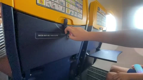 Children close tray tables on a plane in preparation for takeoff Stock Footage 285833166