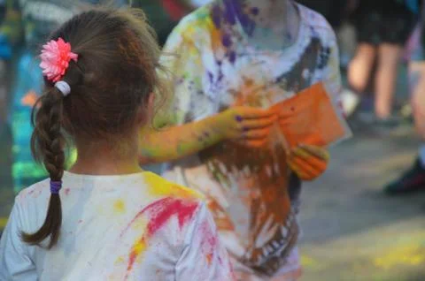 Children in clothes with multi-colored paint stains. Festival of colors on th Foto stock