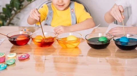 Children color eggs for Easter in glass plates Stock Photos