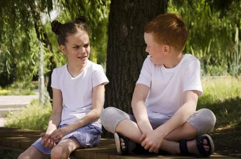 Children communicate while sitting on a bench Stock Photos