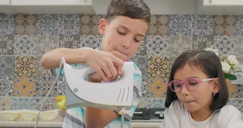 Children cooking dough for baking. A boy beating the dough with a mixer Stock Footage 232045147