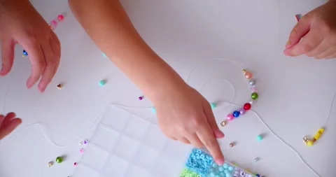 Children Crafting Beaded Necklaces on a Table, Close-Up View Stock Footage 287565068