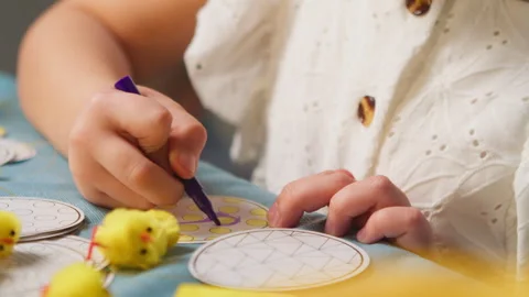 Children decorate Easter eggs while sitting at the table at home, close-up hands Stock Footage 259188587