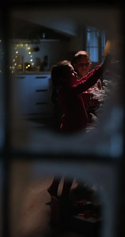 Children decorating Christmas tree with balls, view from snowy window Stock Footage 293616182