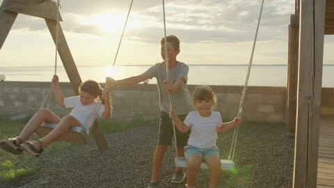 Children of different age and gender ride on a swing. happy childhood concept. Stock Footage 138732172