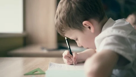 Children do their homework, one sits at the table with notebooks Stock Footage 105099774