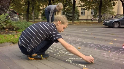 Children draw with chalk on the pavement. In the background, drive cars. Stock-Footage 68342616