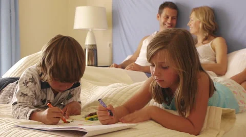 Children drawing in bed while parents watch. Stock Footage 43648942