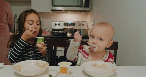 Children eat dessert at the table in the kitchen. Stock Footage 229033374