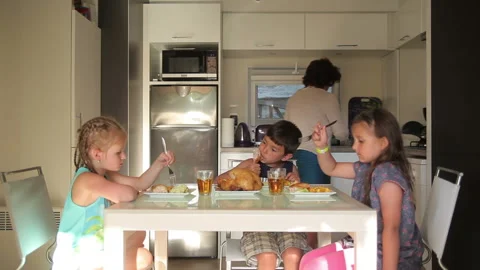 Children eat at the kitchen table served by mom Stock-Footage 115637517