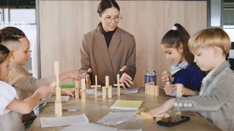 Children engage in building activity with teacher in classroom during afternoon Stock Footage 331308585