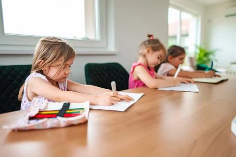Children engaged in creative drawing at a cozy table Stock Photos