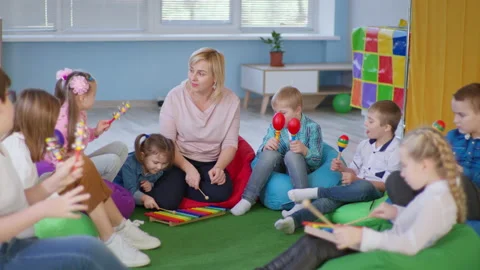 Children enjoying a music lesson in classroom with female teacher, kids with Stock Footage
