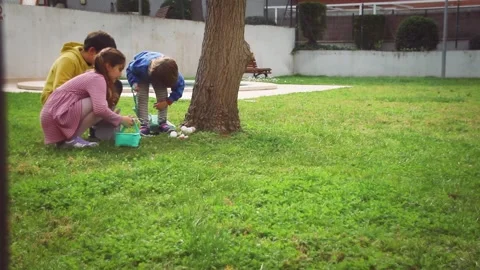 Children excitedly finding easter eggs in the garden Video stock 331718685