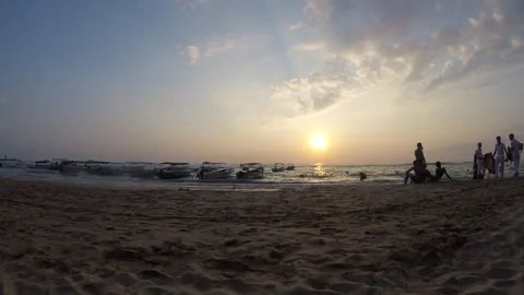 Children Explore the Sandy Beach as the Sun Sets Behind the Gentle Waves Stock Footage 317040433