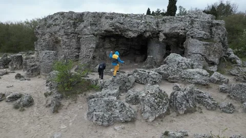 Children exploring rocky cave and limestone formations in sandy landscape Stock Footage 324879304