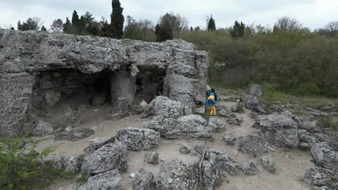 Children exploring rocky cave and limestone formations in sandy landscape Stock Footage 324879400