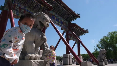 Children with face mask touching stone lion in Beihai Park, Beijing, China. Stock Footage 130992954
