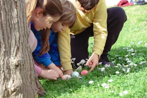Children finding easter eggs during spring outdoor hunt 库存照片