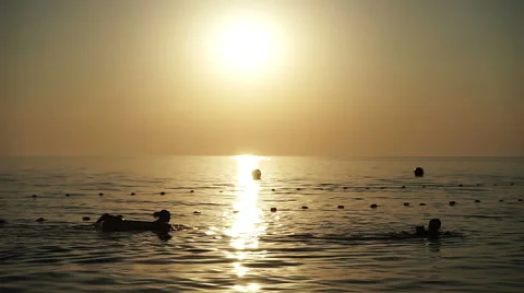 Children floating on a mattresse and with water sleeves in the sea at sunset. HD Stock Footage