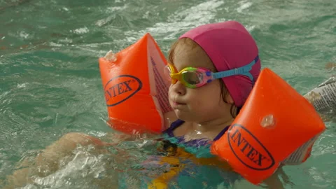 Children in floating suits learn to swim in the school pool.  Swimming Practice Stock Footage 132345326