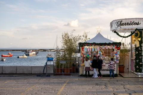 Children gathering at Christmas candy stand by harbor Stock Photos