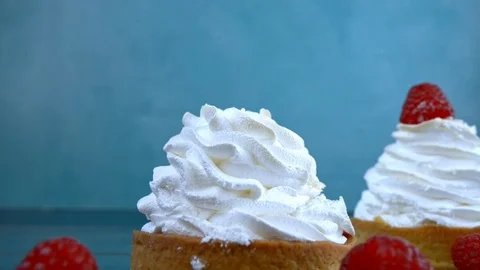 Children hand puts raspberry on a meringue cake on blue background Stock Footage 124824648