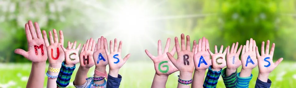 Children Hands Building Word Muchas Gracias Means Thank You, Grass Meadow Stock Photos