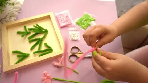 Children hands folding soft pipe cleaner wires into a flower for a mother Stock Footage 342347528