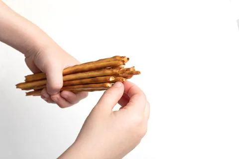 Children hands hold bread bread sticks or straws on a white background Stock Photos