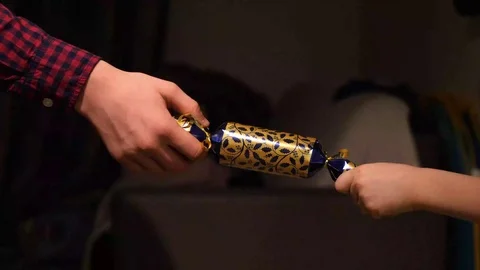 Children hands holding and pulling christmas cracker at home Stock Footage 100670007