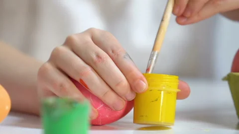 Children hands preparing yellow paint to draw pattern on egg, Easter preparation Stock Footage 99722456