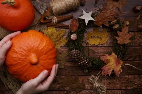 Children hands put a pumpkin on the table with an autumn wreath on the table Stock Photos