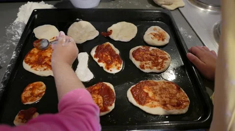 Children hands spread small pizzas with tomato sauce Stock Footage 56754054