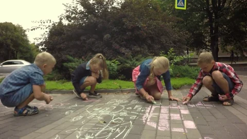 Children happily drawing colored chalk picture on the footpath. 库存影片 79584830