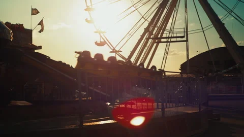 Children have fun at funfair. Carousel and ferris wheel silhouettes at sunset Stock Footage 245745726
