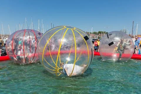 Children have fun inside plastic balloons on the water during a fishing fare Stock Photos