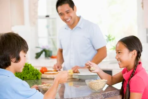 Children having breakfast while dad prepares food Stock Photos